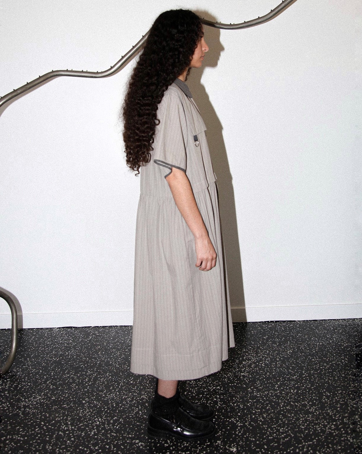 Side view of model wearing the Kkco grey pinstriped Pumice Dress